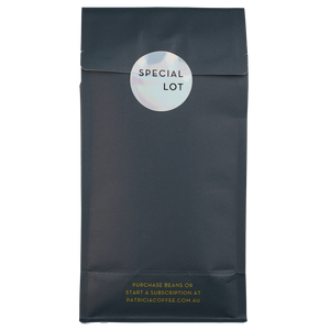 The back of a navy blue recyclable bag containing 1kg of specialty coffee beans. It says in gold 'Purchase beans or start a subscription at patriciacoffee.com.au'. There is also a shiny round sticker that says 'SPECIAL LOT'
