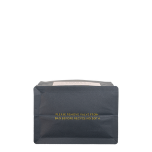 The bottom of a navy blue bag with gold text reading 'PLEASE REMOVE VALVE FROM BAG BEFORE RECYCLING'