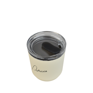 A cream coloured Kinto 240ml reusable coffee tumbler, viewed from above to show the clear plastic lid with silicon stopper in the open position. The Patricia logo printed in black on the front of it.