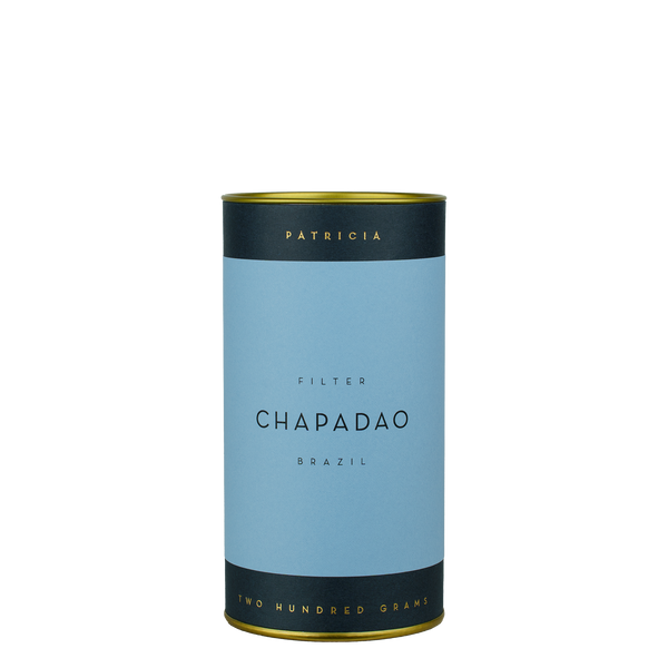 A navy blue cylinder with a blue label describes the roasted coffee beans within. 'PATRICIA' and 'TWO HUNDRED GRAMS' are printed in gold foil.