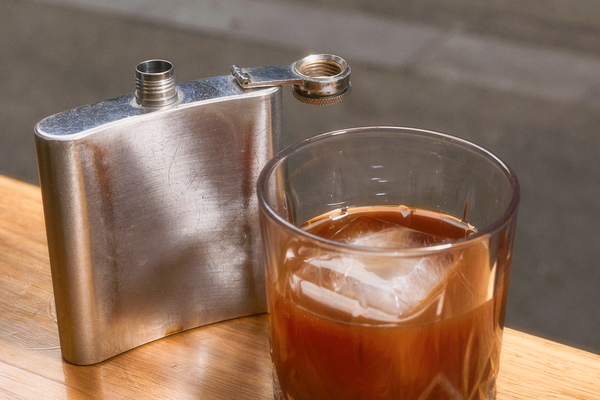 Filter coffee over a large ice cube, in a glass tumbler on Patricia's window sill. The hip flask that it was served from stands next to it.