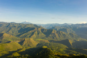 An amazing vista of Inza shows green mountains, with a large snow capped volcano in the distance.