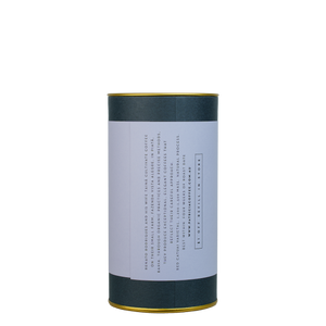 A navy blue cylinder with a light purple label describes the roasted coffee beans within.