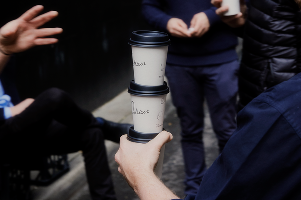 A stack of three takeaway coffees being handed out to customers in Little William St. The names Jane and Brian are visible, handwritten on the cups.