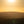 Sunset over a hilly landscape with a warm glow