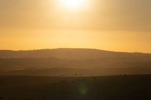 Sunset over a hilly landscape with a warm glow