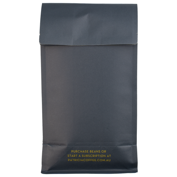The back of a navy blue recyclable bag containing 1kg of specialty coffee beans. It says in gold 'Purchase beans or start a subscription at patriciacoffee.com.au'