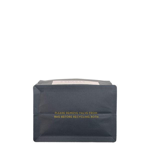 The bottom of a navy blue recyclable bag. It says in gold 'Please remove vale from bag before recycling both'