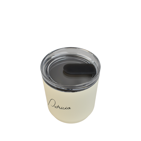 A cream coloured Kinto 240ml reusable coffee tumbler, viewed from above to show the clear plastic lid with silicon stopper in the closed position. The Patricia logo printed in black on the front of it.