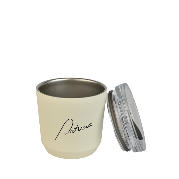 A cream coloured Kinto 240ml reusable coffee tumbler, with the lid off to the side, leaning on the cup. The Patricia logo printed in black on the front of it.