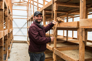 Wicho standing among wooden drying shelves in a greenhouse