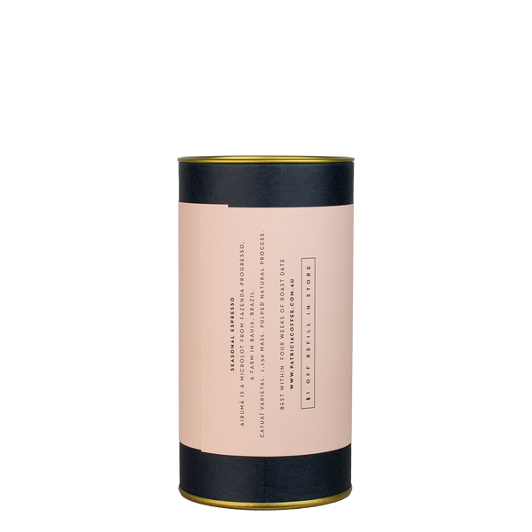 A navy blue cylinder with a pink label describes the espresso coffee beans within.