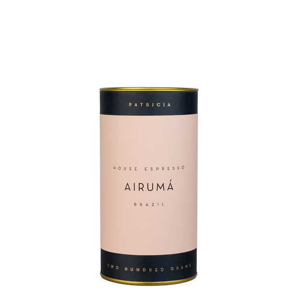 A navy blue cylinder with a pink label describes the espresso coffee beans within. 'PATRICIA' and 'TWO HUNDRED GRAMS' are printed in gold foil.