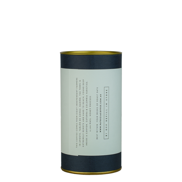 A navy blue cylinder with an lilac label describes the roasted coffee beans within.