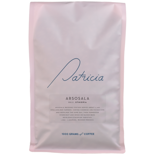 A light pink bag with the Patricia logo, containing 1kg of specialty coffee beans. 