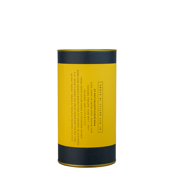A navy blue cylinder with a yellow label describes the roasted coffee beans within.