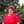 Blanca Lopez stands in front of her lush coffee trees wearing a red blouse.