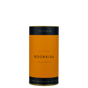 A navy blue cylinder with an orange label describes the filter coffee beans within. 'PATRICIA' and 'TWO HUNDRED GRAMS' are printed in gold foil.