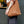 A person wearing a white shirt and dark blue pants carries a brown canvas tote bag with white 'Patricia Coffee Brewers' branding against a dark wall.