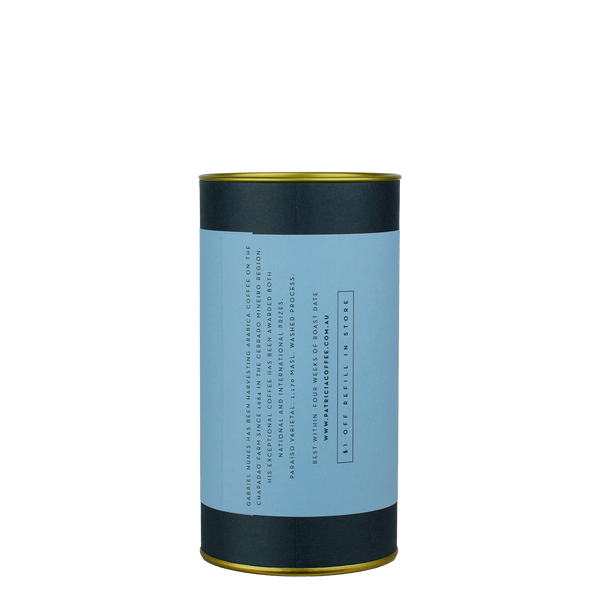 A navy blue cylinder with an red label describes the roasted coffee beans within.