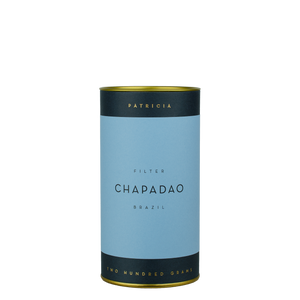 A navy blue cylinder with a blue label describes the roasted coffee beans within. 'PATRICIA' and 'TWO HUNDRED GRAMS' are printed in gold foil.