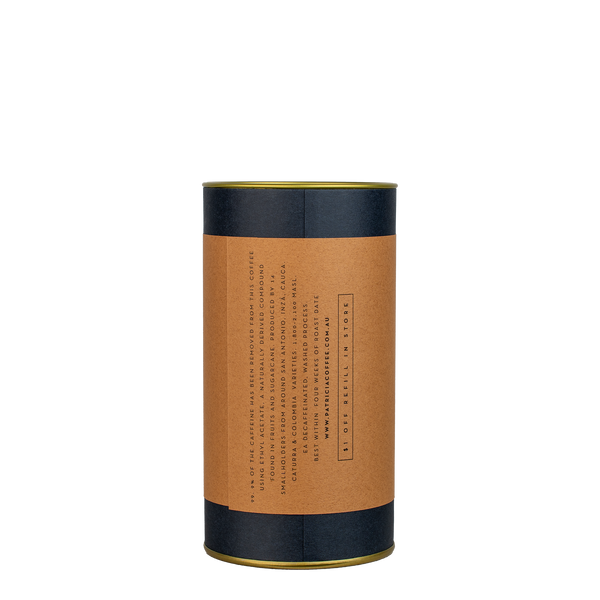 A navy blue cylinder with a brown label describes the roasted decaf coffee beans within.