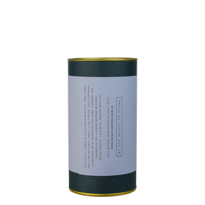 A navy blue cylinder with a lilac label describes the roasted coffee beans within.