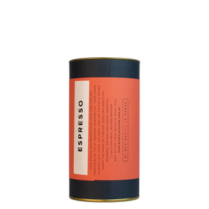 A navy blue cylinder with a red label describes the espresso coffee beans within.