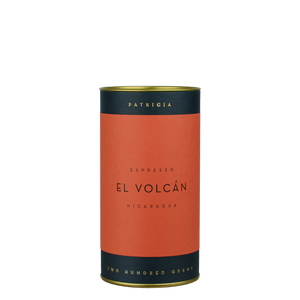 A navy blue cylinder with a red label describes the roasted coffee beans within. 'PATRICIA' and 'TWO HUNDRED GRAMS' are printed in gold foil.