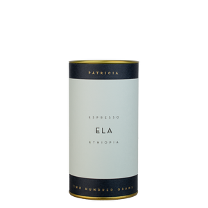 A navy blue cylinder with a light blue label describes the roasted coffee beans within. 'PATRICIA' and 'TWO HUNDRED GRAMS' are printed in gold foil.