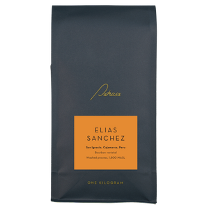 A navy blue recyclable bag containing 1kg of specialty coffee beans. It has the Patricia logo in gold, the coffee's name on an orange sticker, and 'One kilogram' in gold underneath.