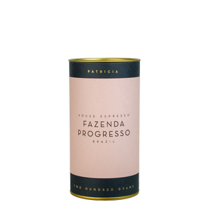Cylindrical coffee canister with 'Fazenda Progresso' branding on a pink label.