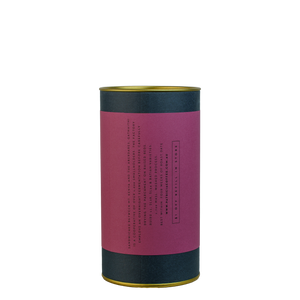 A navy blue cylinder with a pruple label describes the roasted coffee beans within.