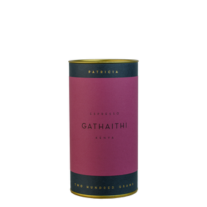 A navy blue cylinder with a purple label describes the roasted coffee beans within. 'PATRICIA' and 'TWO HUNDRED GRAMS' are printed in gold foil.