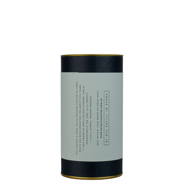 A navy blue cylinder with a light blue label describes the filter coffee beans within.