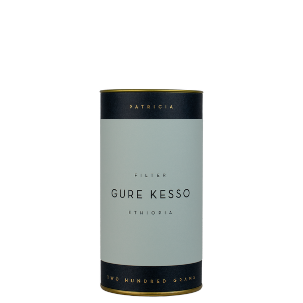 A navy blue cylinder with a light blue label describes the filter coffee beans within. 'PATRICIA' and 'TWO HUNDRED GRAMS' are printed in gold foil.