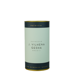 A navy blue cylinder with a light blue label describes the roasted coffee beans within. 'PATRICIA' and 'TWO HUNDRED GRAMS' are printed in gold foil.