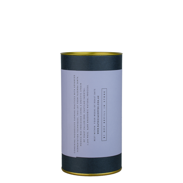 A navy blue cylinder with a purple label describes the roasted coffee beans within.