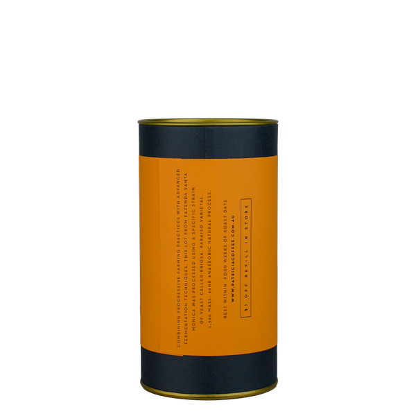 A navy blue cylinder with an orange label describes the roasted coffee beans within.