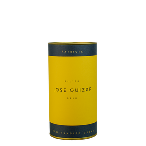 A navy blue cylinder with a yellow label describes the roasted coffee beans within. 'PATRICIA' and 'TWO HUNDRED GRAMS' are printed in gold foil.