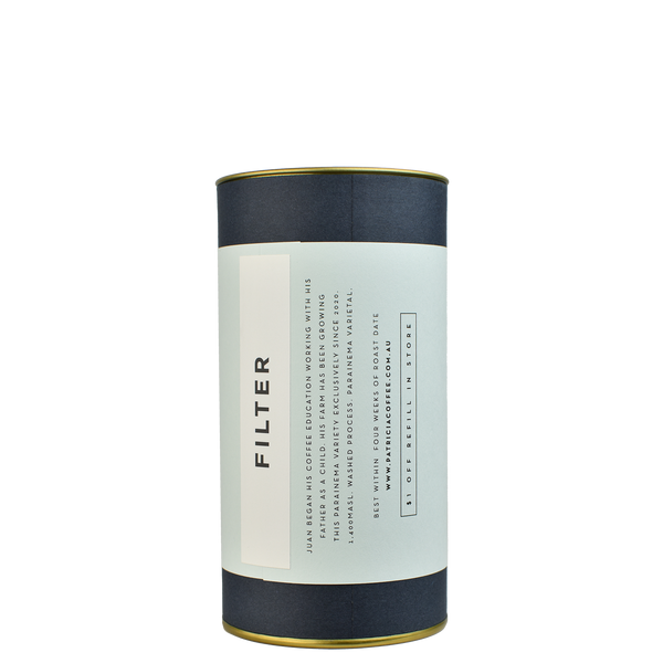 A navy blue cylinder with a light blue label describes the filter coffee beans within.