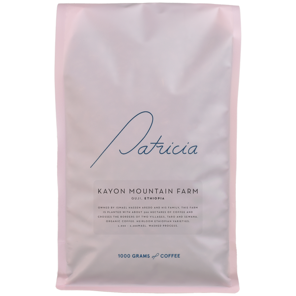 A light pink bag with the Patricia logo, containing 1kg of specialty coffee beans. 