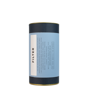 A navy blue cylinder with a blue label describes the filter coffee beans within.