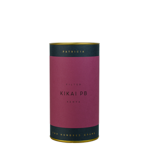 A navy blue cylinder with a purple label describes the roasted coffee beans within. 'PATRICIA' and 'TWO HUNDRED GRAMS' are printed in gold foil.