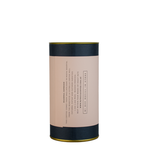 A navy blue cylinder with a pink label describes the espresso coffee beans within.
