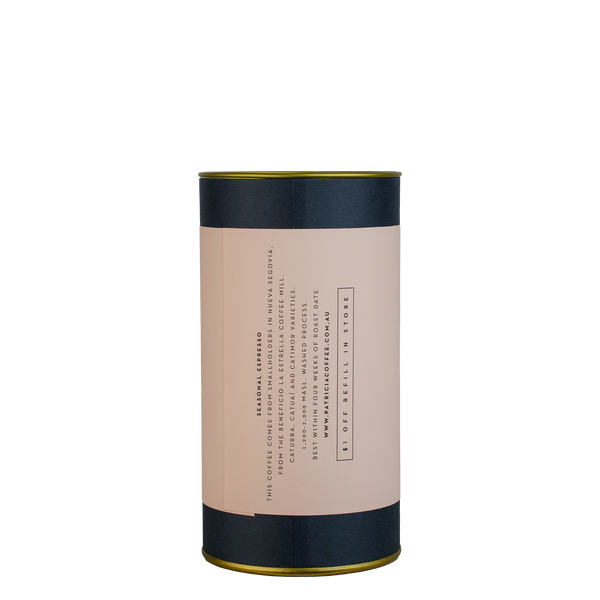 A navy blue cylinder with a pink label describes the espresso coffee beans within.