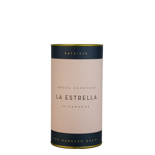 A navy blue cylinder with a pink label describes the espresso coffee beans within. 'PATRICIA' and 'TWO HUNDRED GRAMS' are printed in gold foil.