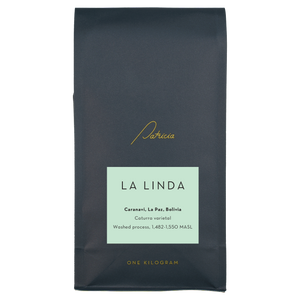 A navy blue recyclable bag containing 1kg of specialty coffee beans. It has the Patricia logo in gold, the coffee's name on a light blue sticker, and 'One kilogram' in gold underneath.