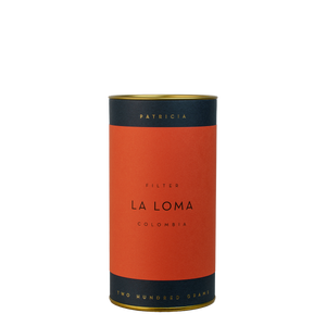 A navy blue cylinder with a red label describes the roasted coffee beans within. 'PATRICIA' and 'TWO HUNDRED GRAMS' are printed in gold foil.