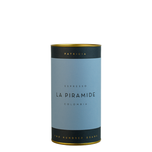 A navy blue cylinder with a blue label describes the roasted coffee beans within. 'PATRICIA' and 'TWO HUNDRED GRAMS' are printed in gold foil.